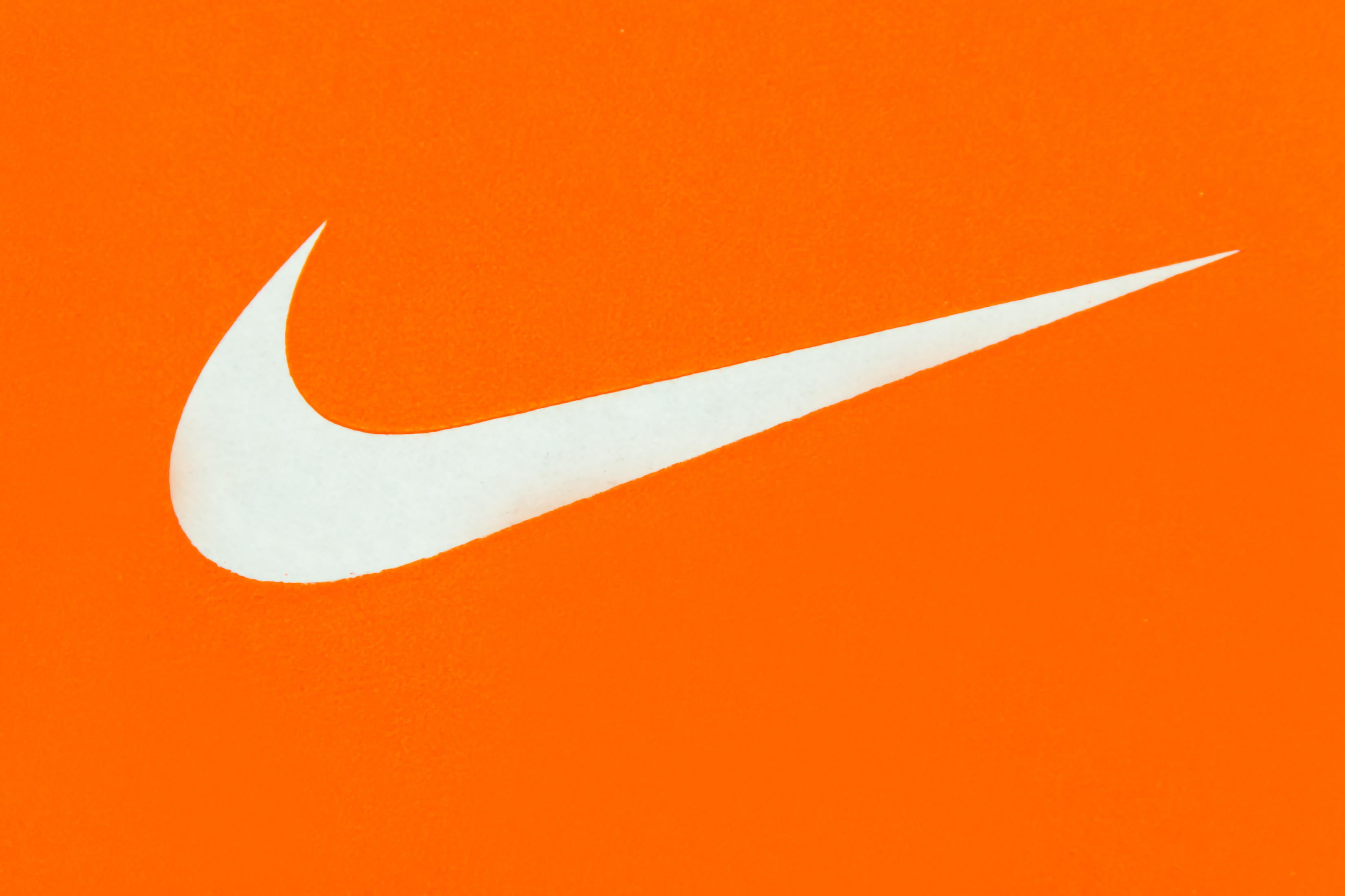 ナイキ　ロゴ　(White Nike Logo on Orange Background;Nike, Inc.)